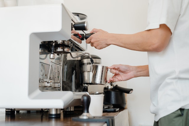 A person undertakes cleaning espresso machine with vinegar